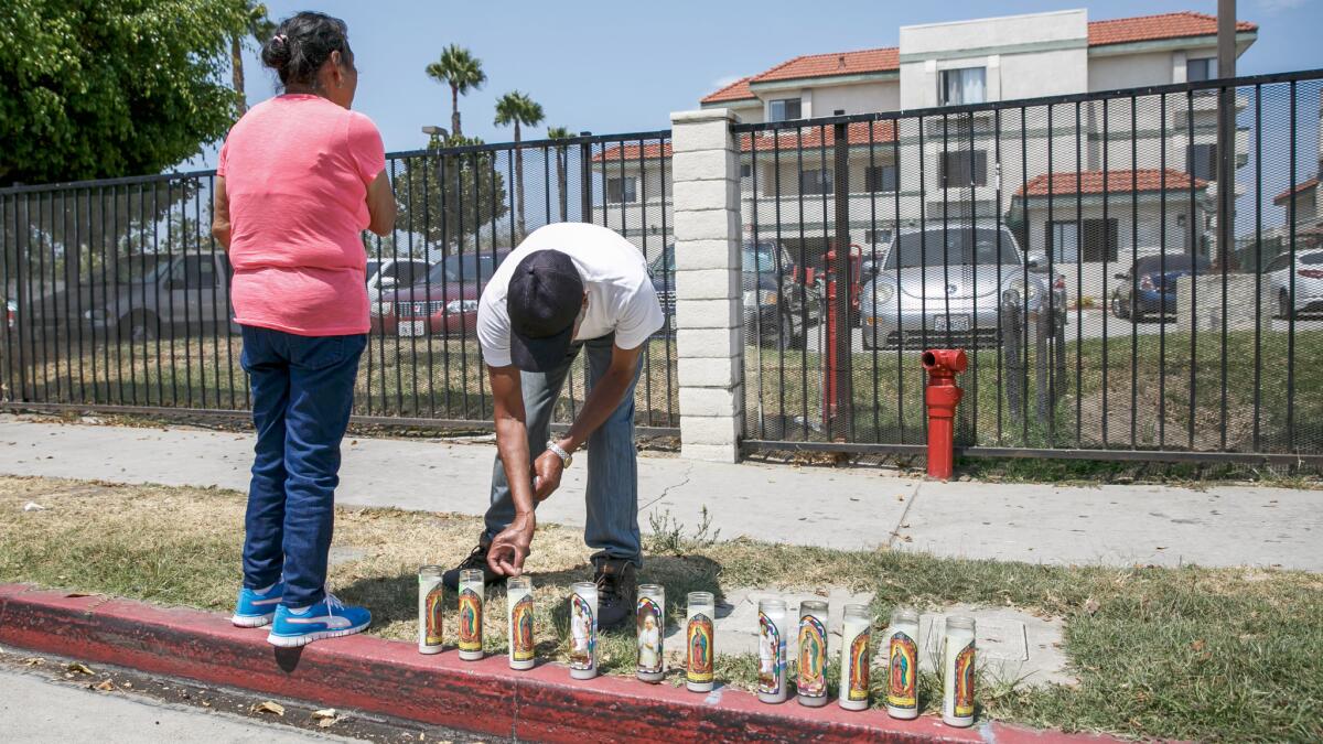 Jose Luis Bermejo places a candle for the woman and two children who were hit and killed by a motorist on West La Jolla Street in Placentia.