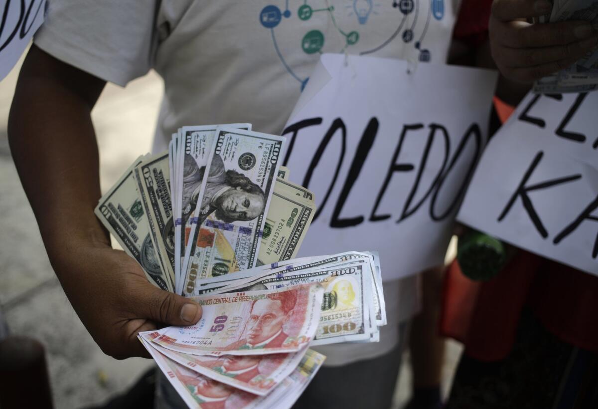A man holds fake dollars and Peruvian currency during a demonstration against former President Alejandro Toledo, in Lima, Peru, on Feb. 9, 2017.