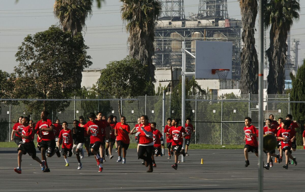 Students jog on the playground at Elizabeth Hudson K-8 Elementary School in Long Beach. The school sits near the Tesoro oil refinery, the Terminal Island Freeway, a railroad line and the Port of Long Beach. (Don Bartletti / Los Angeles Times)