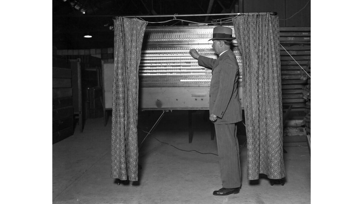 On Oct. 2, 1928, Los Angeles County Register William Kerr demonstrates how to use of a new kind of voting machine.