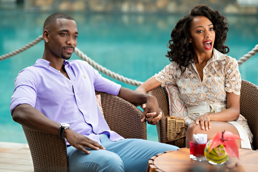 A man and woman sit next to a pool, holding hands