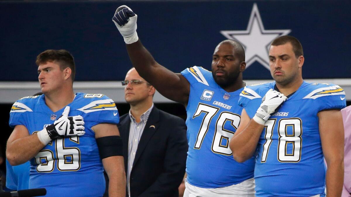 Chargers' Russell Okung raises his fist as he stands between Dan Feeney, left, and Michael Schofield during the playing of the national anthem before a game against the Dallas Cowboys on Nov. 23.