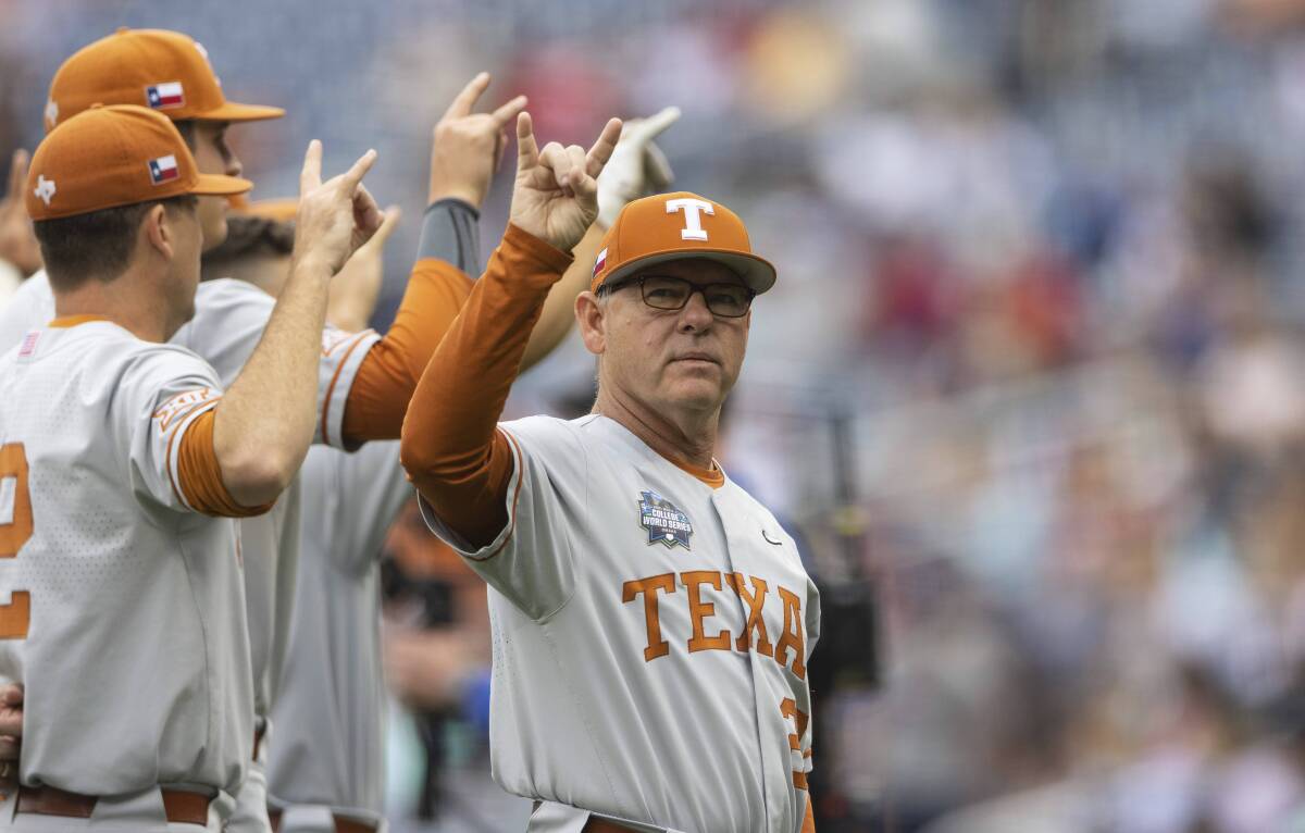FILE -T exas head coach David Pierce signals the crowd as they sing "The Eyes of Texas" before playing against Mississippi State during a baseball game in the College World Series Saturday, June 26, 2021, at TD Ameritrade Park in Omaha, Neb. Texas is the consensus No. 1 team heading into Friday's, Feb. 18, 2022. opening of the college baseball season. (AP Photo/Rebecca S. Gratz, File)