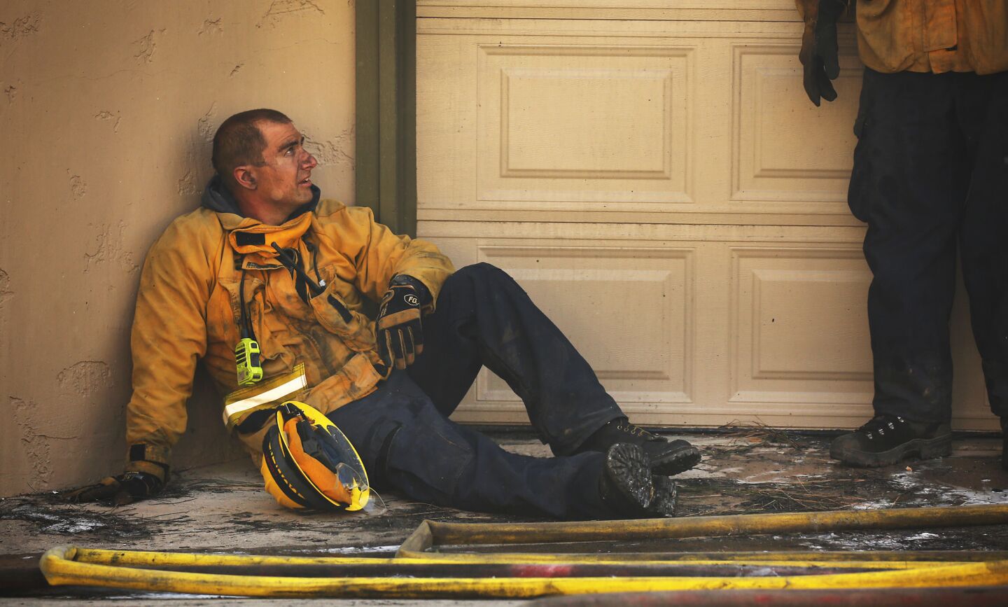 Ventura County Firefighter Aaron Cohen catches his breath after fighting to save homes along Cobblestone Drive near Foothill Road in Ventura.