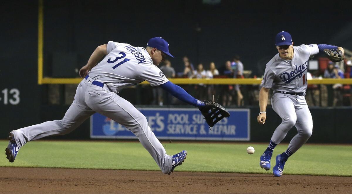 Dodgers first baseman Joc Pederson (31) makes an error on a grounder hit by Arizona Diamondbacks' David Peralta as Dodgers second baseman Enrique Hernandez, right, moves in to help out during the first inning on Wednesday in Phoenix.
