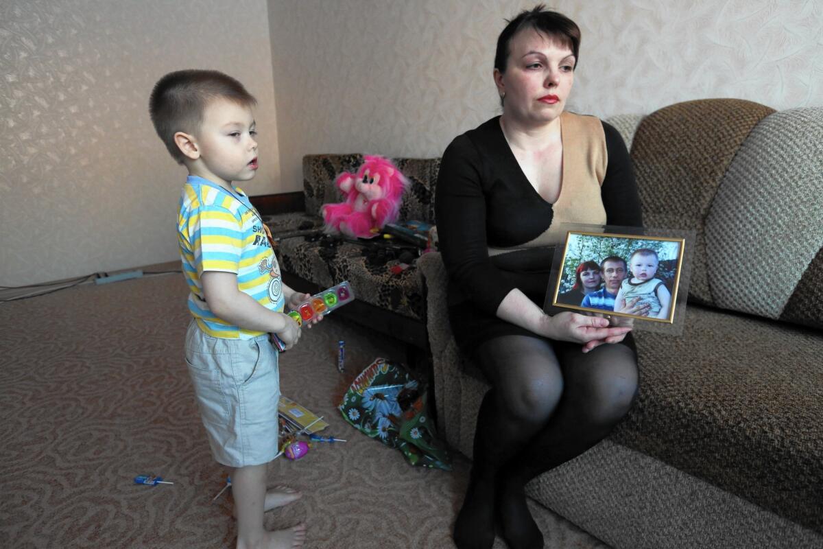 Natalya Zhitineva and her son, Denis, with a photo of them together with Natalya's husband, Alexander Zhitinev, who went to fight in Ukraine.