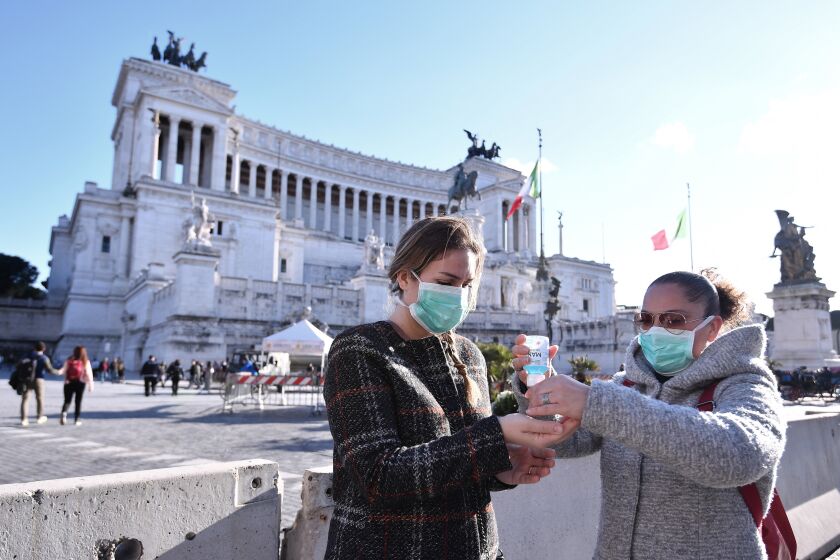 Women wearing face mask disinfect their hands in central Piazza Venezia, in Rome, Sunday, March 8, 2020. Italy announced a sweeping quarantine early Sunday for its northern regions, igniting travel chaos as it restricted the movements of a quarter of its population in a bid to halt the new coronavirus' relentless march across Europe. (Alfredo Falcone/LaPresse via AP)