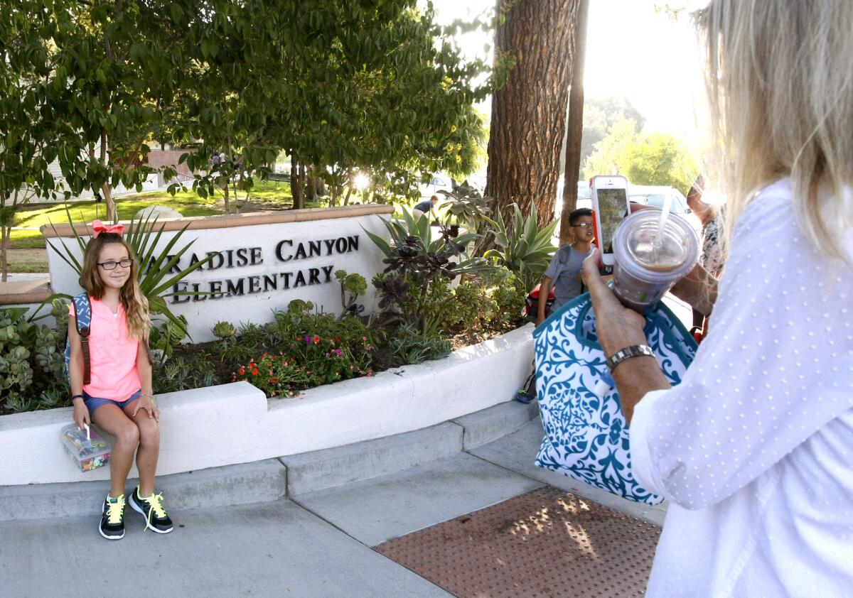 Third grader Willa Chandler's mother takes a photo of her in front of the school sign on the first day of school at Paradise Canyon Elementary School in La Cañada Flintridge on Tuesday, Aug. 12, 2014.