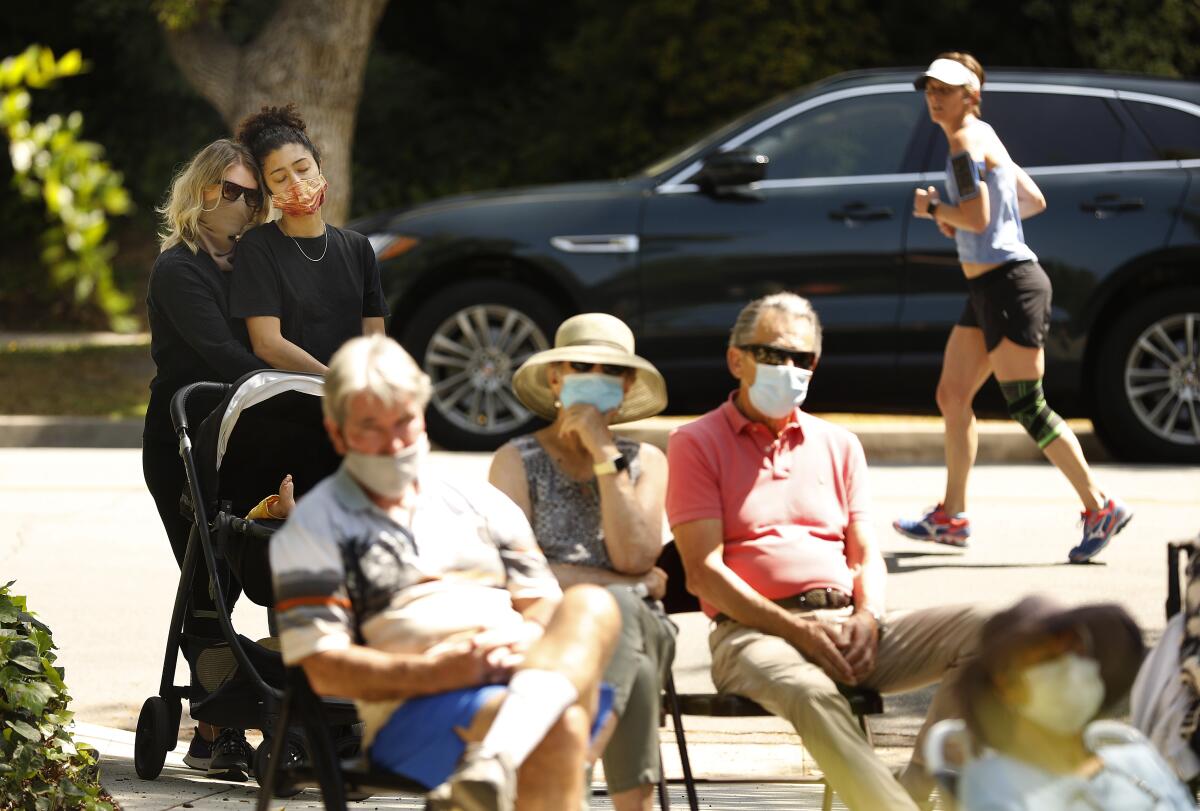 A socially distanced and mask-wearing crowd gathers on a lawn in Pasadena.
