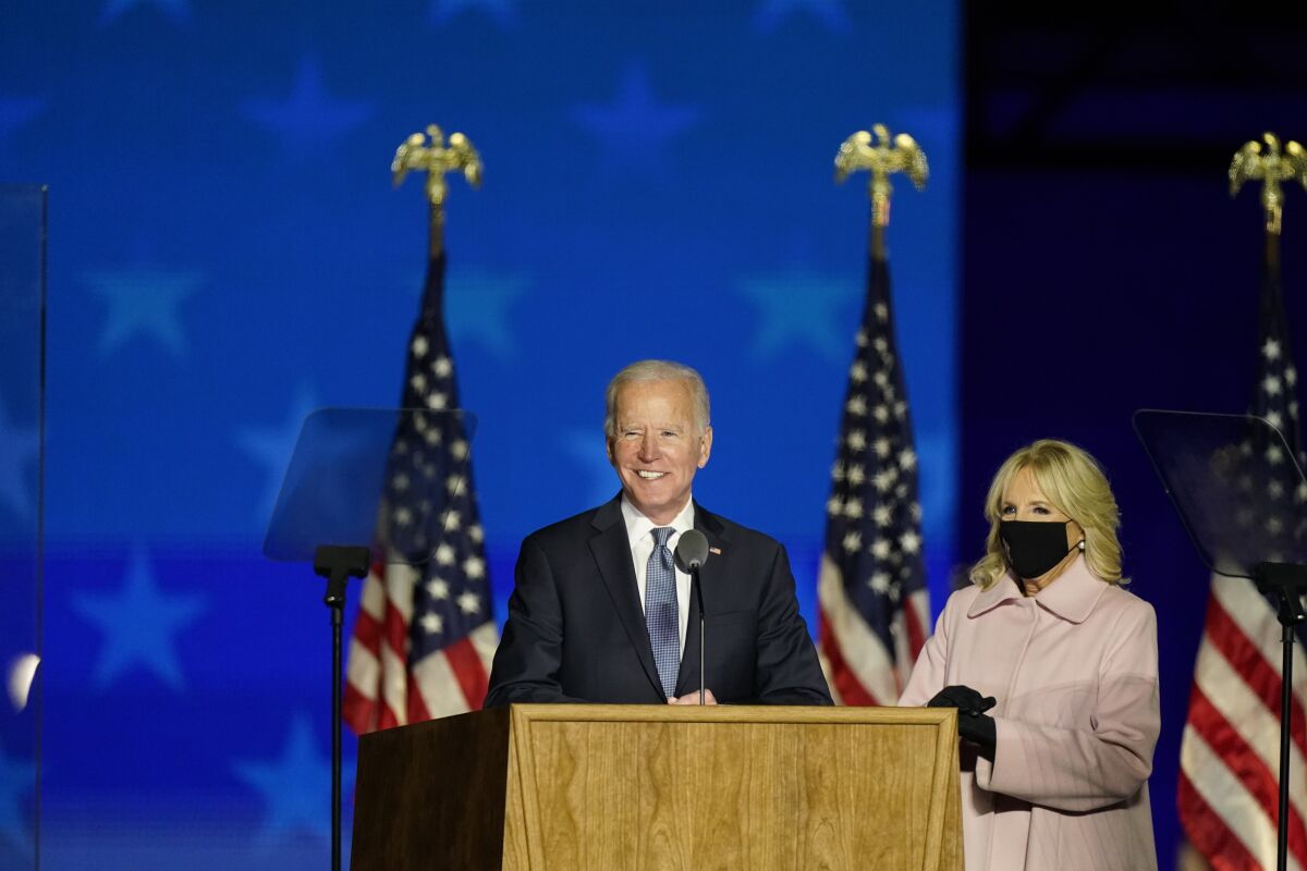 Joe Biden speaks at a lectern with wife Jill by his side.