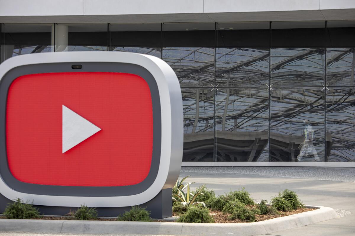 SoFi Stadium is reflected in the glass exterior of the new YouTube Theater.