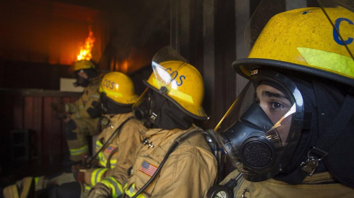 Newly hired firefighters go through a live burn training exercise Wednesday in a flashover container during a six-week fire academy run by the Costa Mesa Fire Department.