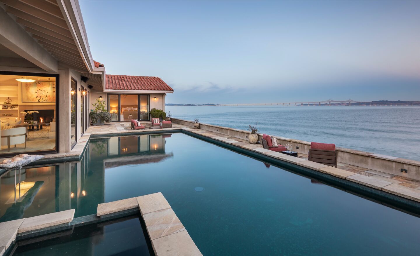 A swimming pool, house and deck overlooking the bay.