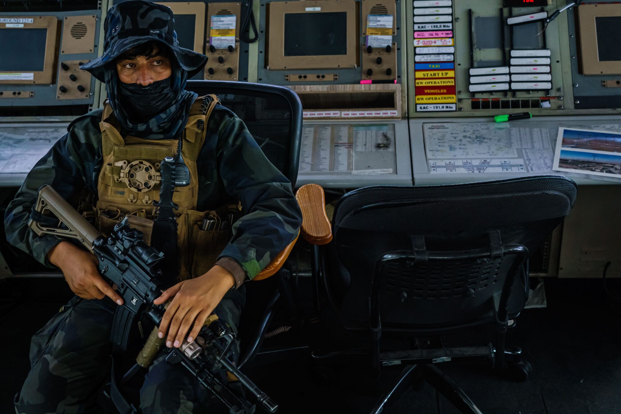 A fighter with a rifle sits inside an airport control tower