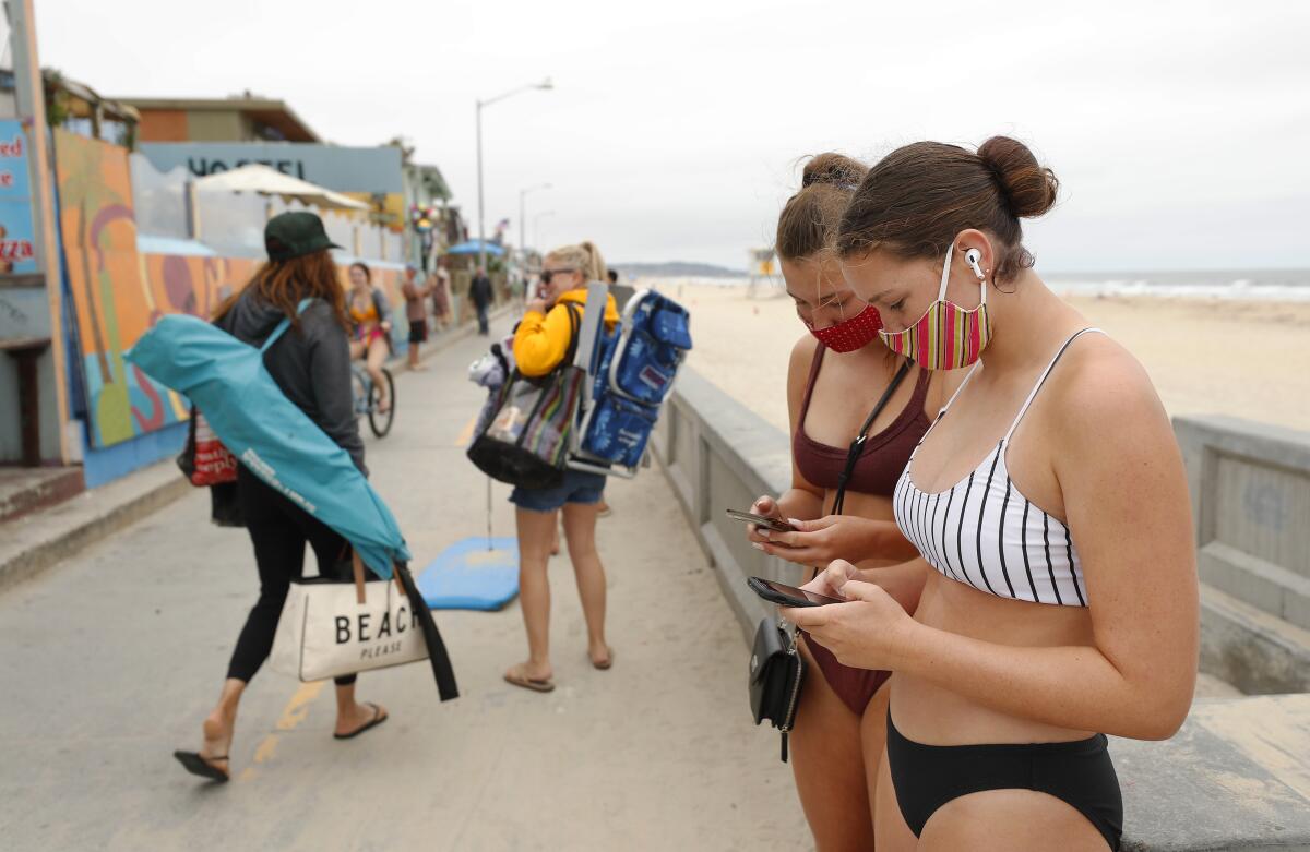 Calyssa Hill, left, and Hadley Hall, wear masks on the Pacific Beach boardwalk in San Diego on June 24, 2020.