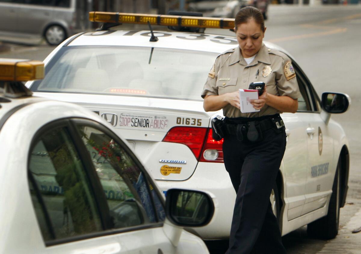A Los Angeles traffic officer walks back to her vehicle after a converstion with another officer on Echo Park Ave.