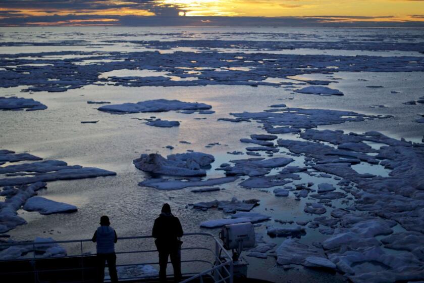 FILE - In this July 21, 2017 file photo, researchers look out from the Finnish icebreaker MSV Nordica as the sun sets over sea ice floating on the Victoria Strait along the Northwest Passage in the Canadian Arctic Archipelago. After 24 days at sea and a journey spanning more than 10,000 kilometers (6,214 miles), the Finnish icebreaker MSV Nordica has set a new record for the earliest transit of the fabled Northwest Passage. The once-forbidding route through the Arctic, linking the Pacific and the Atlantic oceans, has been opening up sooner and for a longer period each summer due to climate change. Sea ice that foiled famous explorers and blocked the passage to all but the hardiest ships has slowly been melting away in one of the most visible effects of man-made global warming.(AP Photo/David Goldman, File)