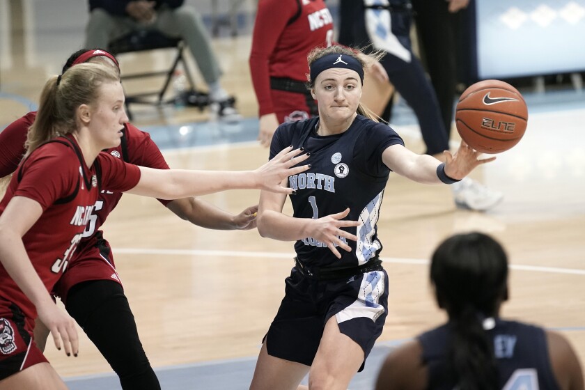 North Carolina guard Alyssa Ustby (1) passes while North Carolina State center Elissa Cunane (33) reaches in during the second half of an NCAA college basketball game in Chapel Hill, N.C., Sunday, Feb. 7, 2021. (AP Photo/Gerry Broome)