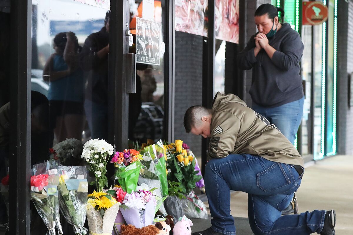 U.S. Army veteran Latrelle Rolling and Jessica Lang pray at Young’s Asian Massage, where four people were killed.