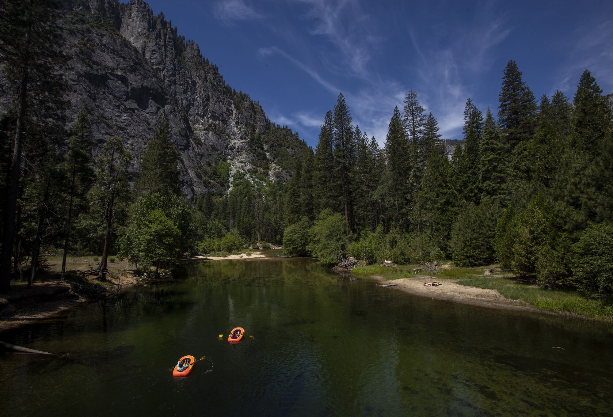 The rafters row down the Merced River in Yosemite Valley.