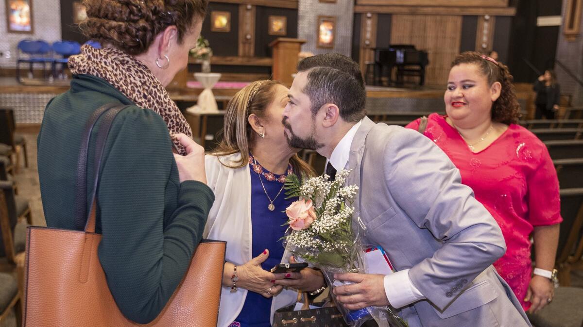 Vanguard University nursing graduate Miguel Rosado gets a kiss from his mother, Ana Zelia Gonzalez, after a pinning ceremony Thursday. Both are Salvadoran refugees.