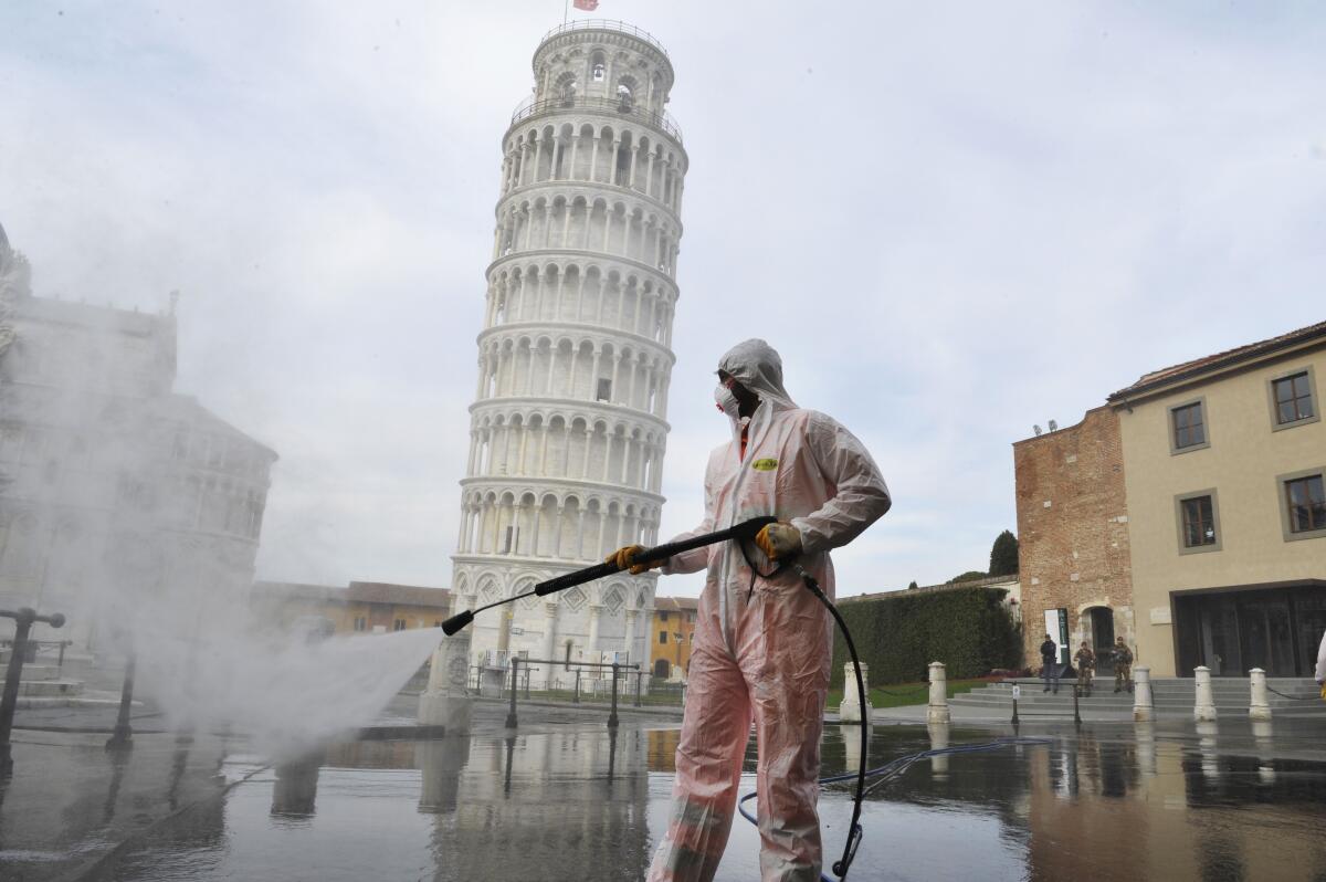 A worker carries out sanitation operations for the coronavirus emergency near the Tower of Pisa amid a devastating coronavirus outbreak.