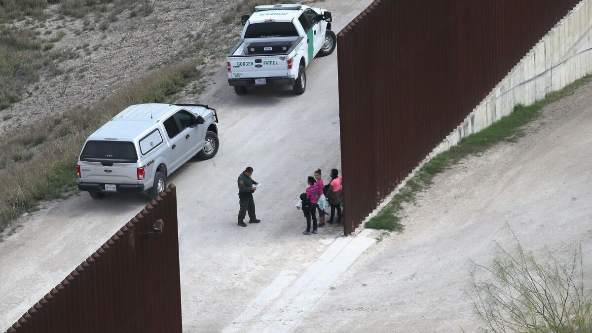 U.S. Border Patrol agents question undocumented immigrant families at the U.S.-Mexico border fence on February 21, near McAllen, Texas.