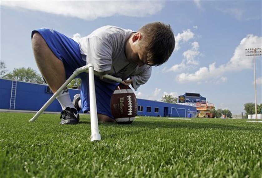 In this photo taken Aug. 12, 2010, Indiana State kicker Brett Sheldon places a football under a tee as the kickers practice kicking field goals during NCAA college football practice in Terre Haute, Ind. Sheldon is the 22-year-old backup kicker for the Sycamores and it so happens that he was born with short arms and hands with three fingers. The birth defect didn't stop him from chasing his dream of playing college football and making the team as a walk-on. (AP Photo/Darron Cummings)