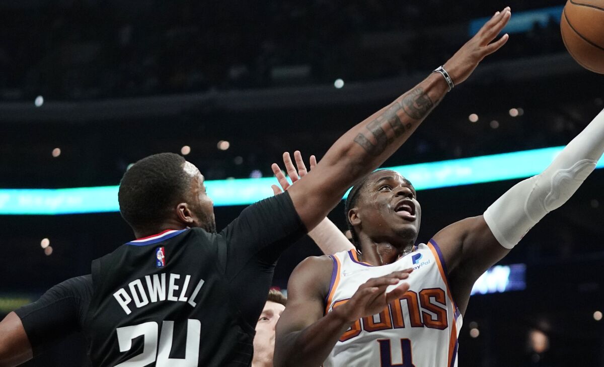 Phoenix Suns guard Aaron Holiday shoots as Los Angeles Clippers forward Norman Powell defends 