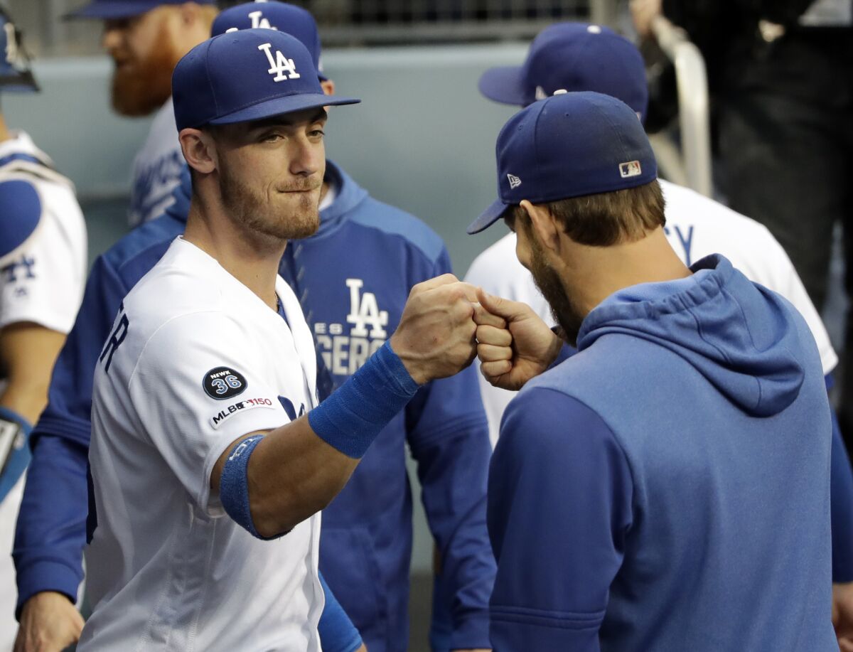 Dodgers' Cody Bellinger, left, bumps fist with Clayton Kershaw before a game June 21 at Dodger Stadium.