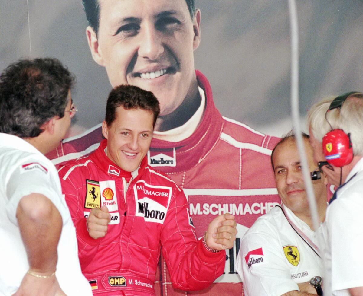 German Formula One driver Michael Schumacher jokes with Ferrari mechanics in front of a large photo of himself during the first day of testing after the Portuguese Grand prix at Estoril Tuesday, September 24, 1996.