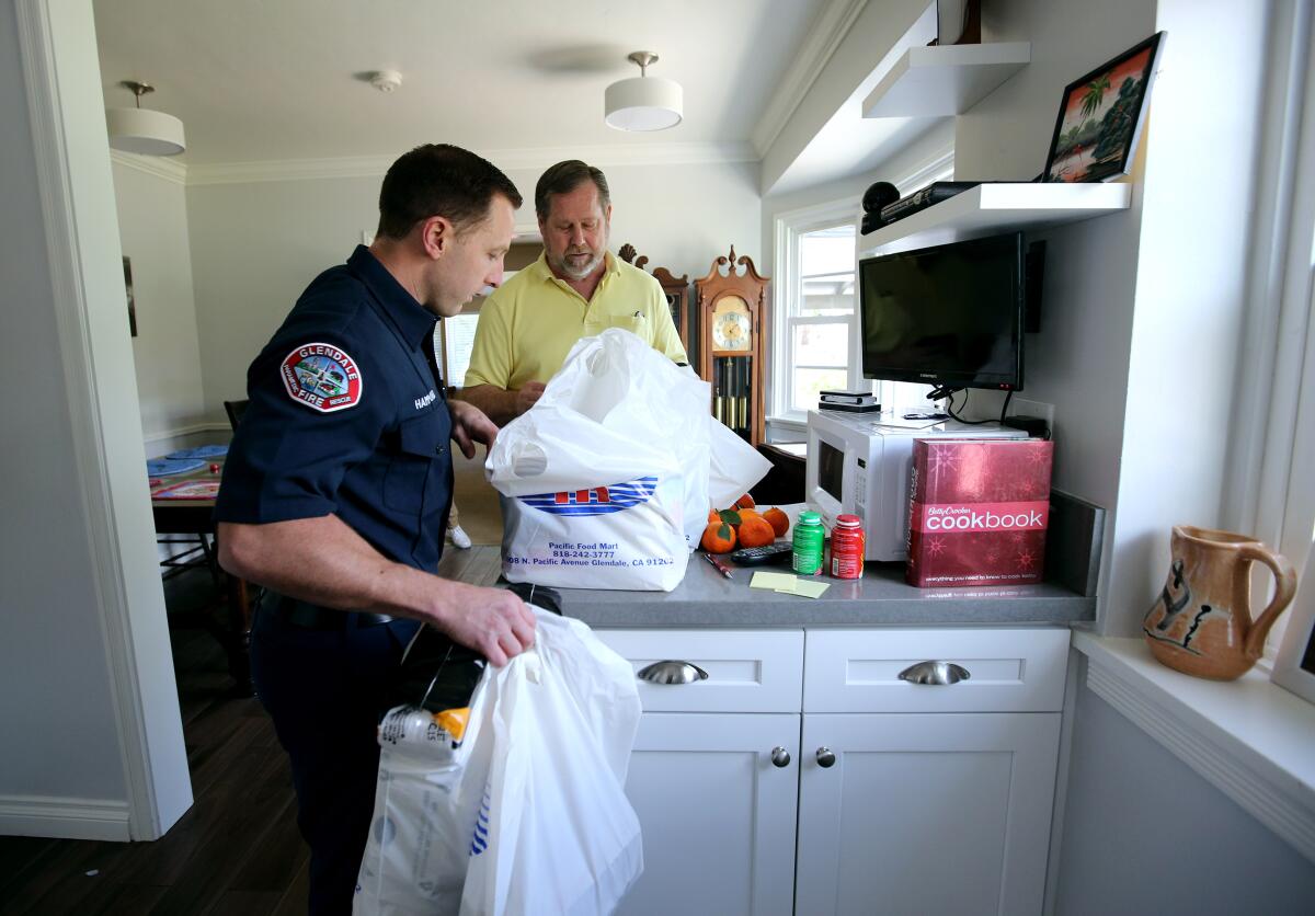 Glendale Firefighter-Paramedic Spencer Hammond delivers groceries to 64-year-old Jim Rohrig. The Glendale Fire Department has offered to deliver groceries to the city's vulnerable population who are sheltering in place because of the coronavirus. 