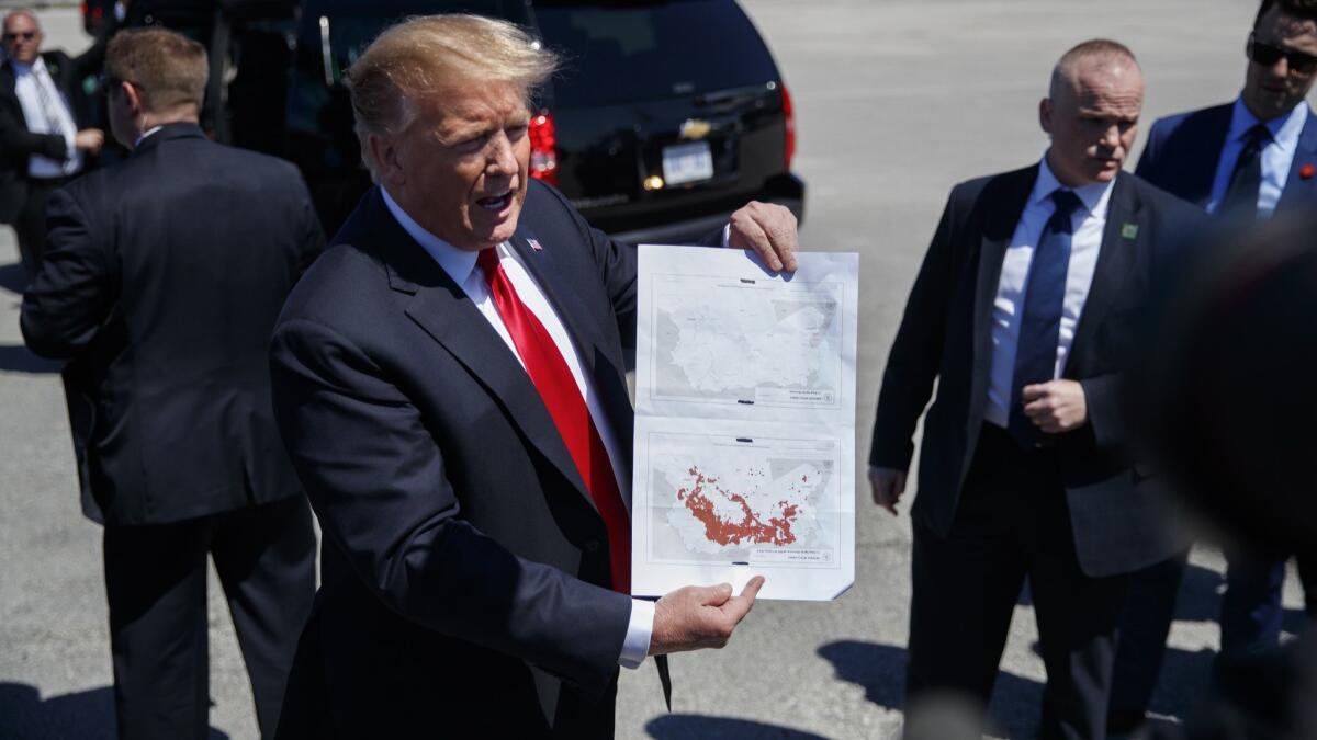 President Trump holds maps of Syria after arriving in West Palm Beach, Fla, on Friday.