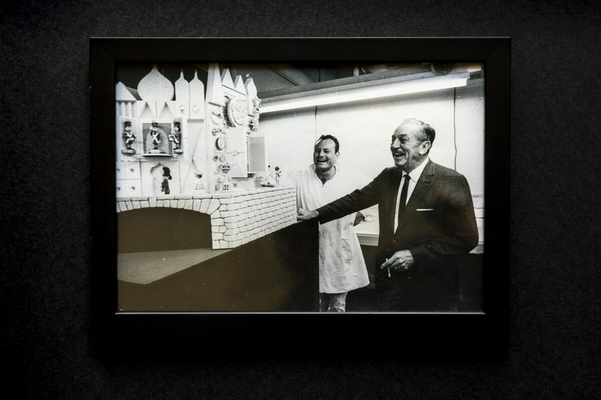 Rolly Crump stands beside Walt Disney and a model of It’s a Small World. 