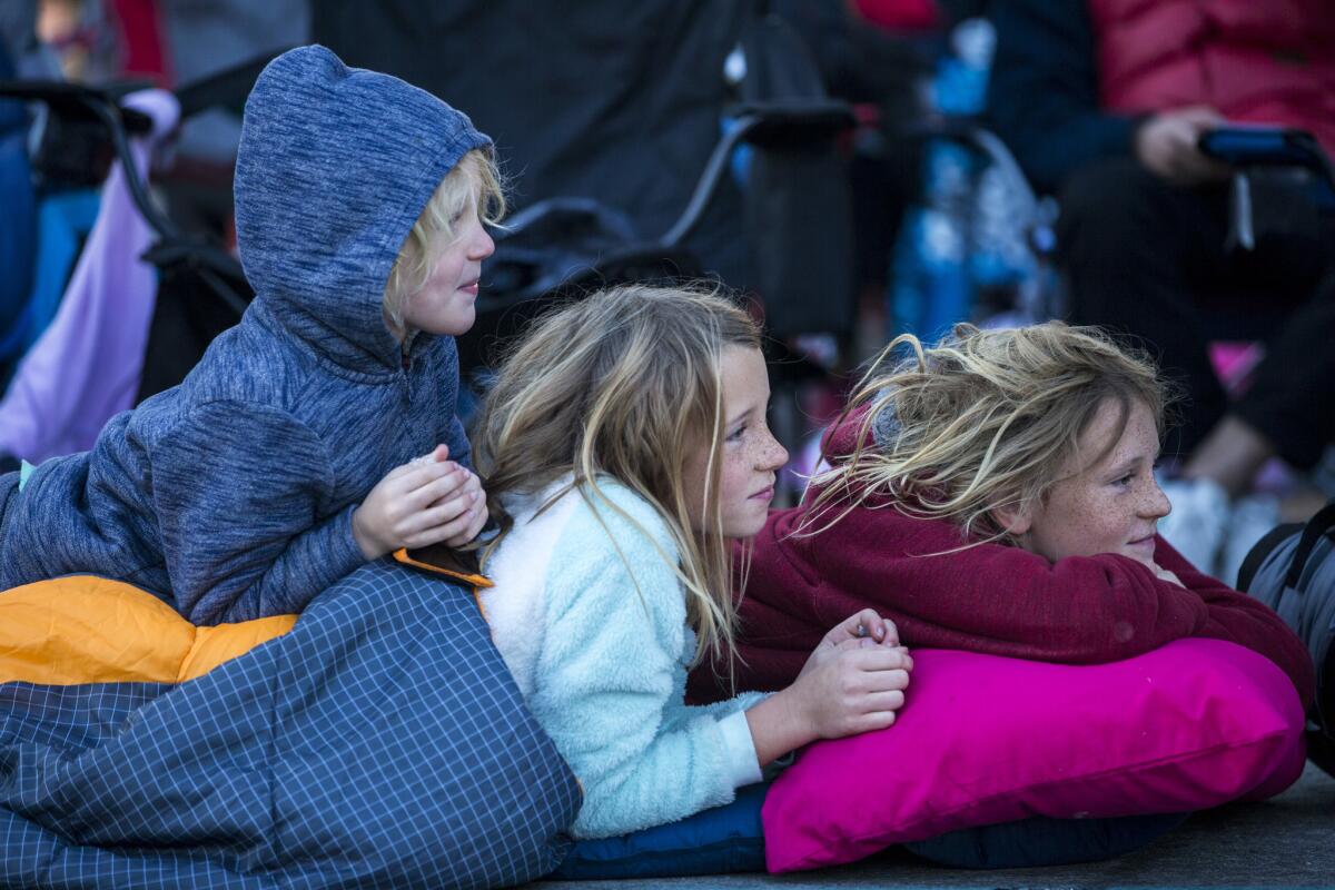 Ephram Wright, 11, right, Payson Wright, 9, center, and Lucas Wright, 6, wait for floats during the 2018 Rose Parade.