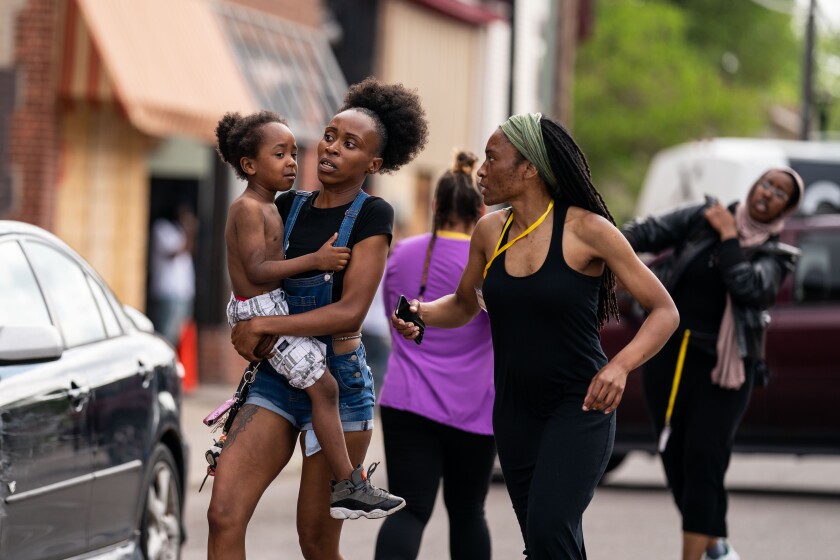 Mileesha Smith, 30, of Minneapolis, carries a child while she and others scramble after gunshots ring out 