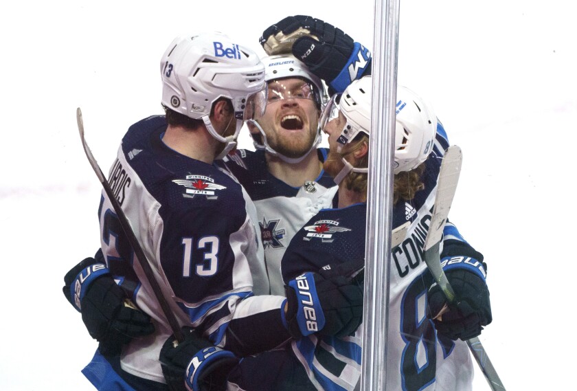 Winnipeg Jets' Pierre-Luc Dubois, left, celebrates his winning goal with teammates Nikolaj Ehlers, centre, and Kyle Connor to defeat the Montreal Canadiens during overtime NHL hockey game action in Montreal, Thursday, March 4, 2021. (Paul Chiasson/The Canadian Press via AP)