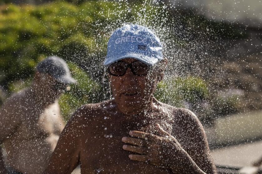A bather takes a shower during a hot day at Alimos beach near Athens, Friday, July 14, 2023. Temperatures were starting to creep up in Greece, where a heatwave was forecast to reach up to 44 degrees Celsius in some parts of the country over the weekend. (AP Photo/Petros Giannakouris)