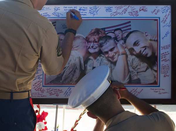 Marines write condolence messages on a photo of Laura Froehlich at Riverside National Cemetery.