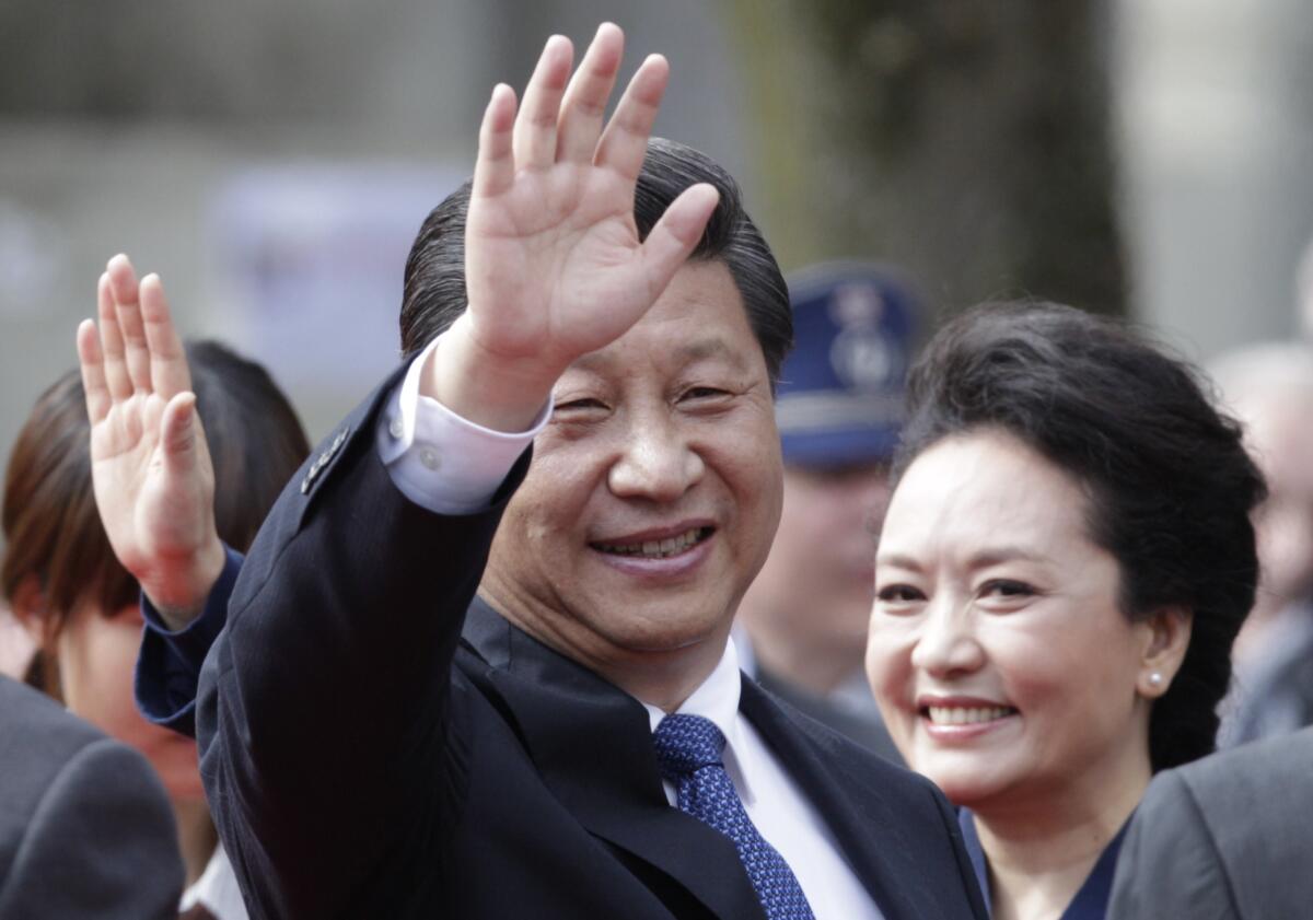 China's President Xi Jinping, left, and his wife Peng Liyuan wave to the crowd at the Burg square in Bruges, Belgium.