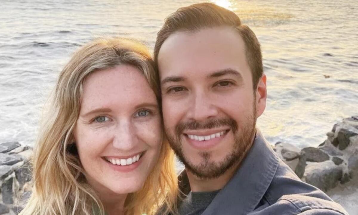 A woman and a man smiling with the ocean in the background