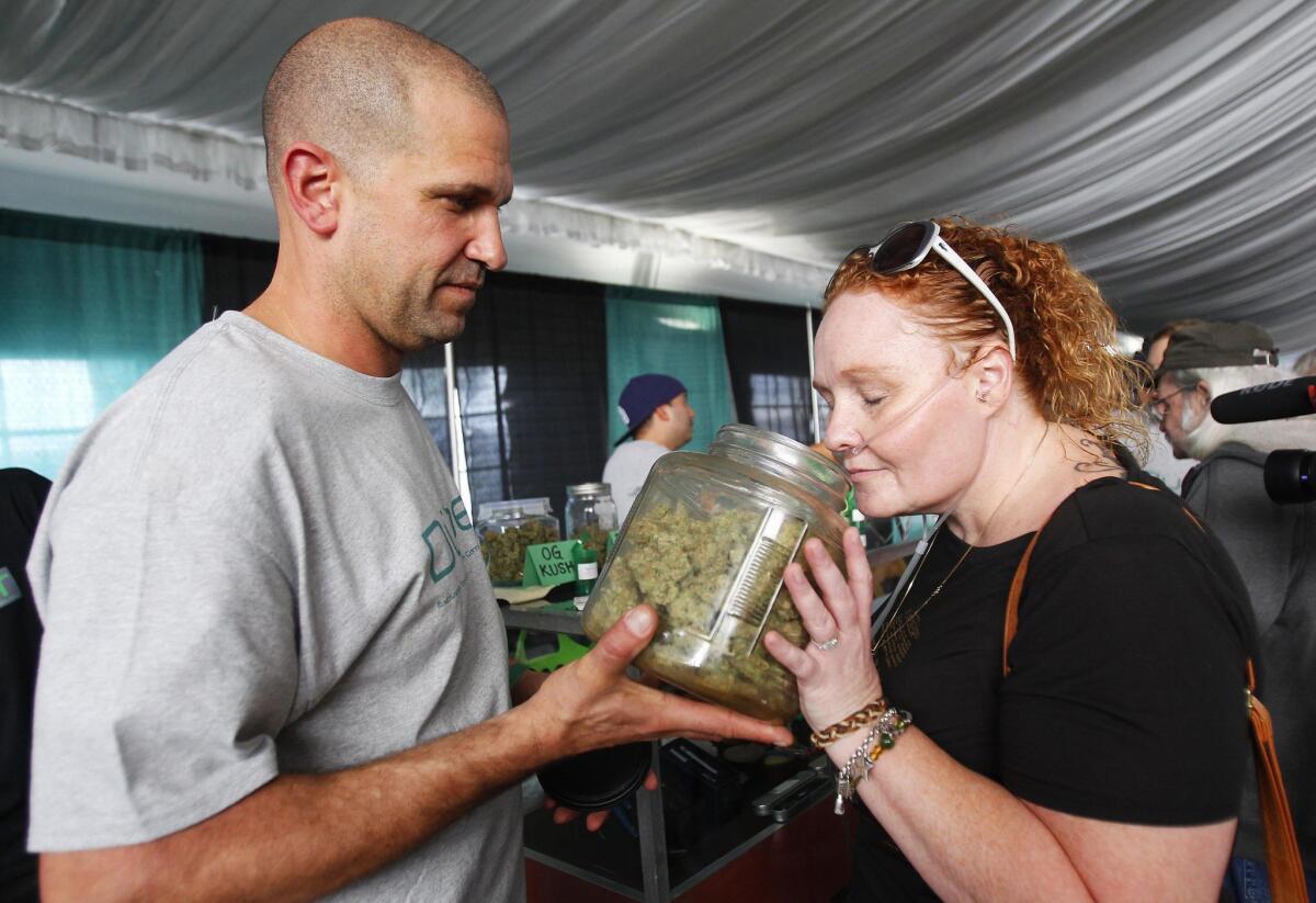 Alicia Tucker, right, smells marijuana as Robert Kirk of Duber Collective helps her out at PotLuck, a Medical Cannabis Expo.