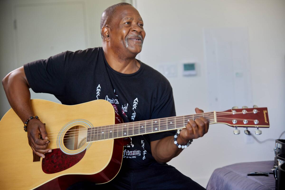 Milo Oliver, 58, plays guitar at Trinity Place, a new apartment building in San Diego for formerly homeless seniors.
