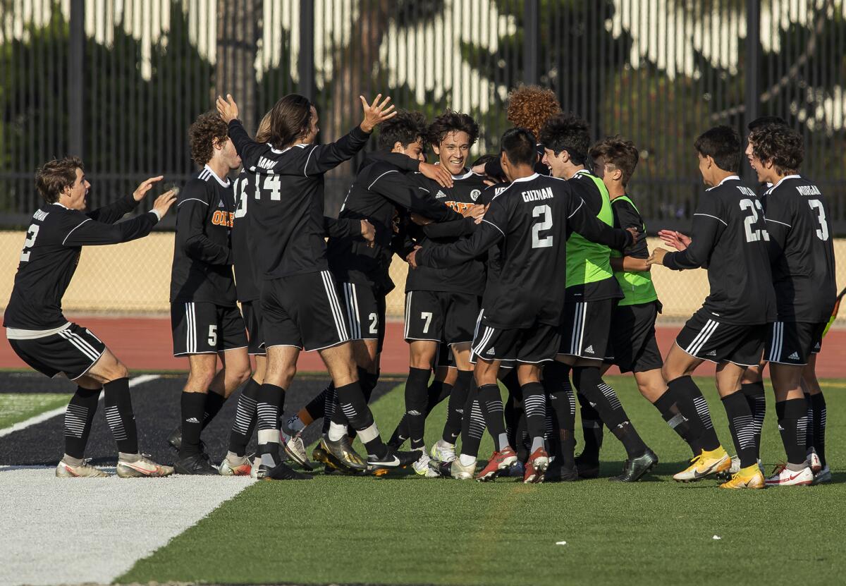 Huntington Beach's Carson Dykes, center, is mobbed by his team after scoring a goal against Estancia.