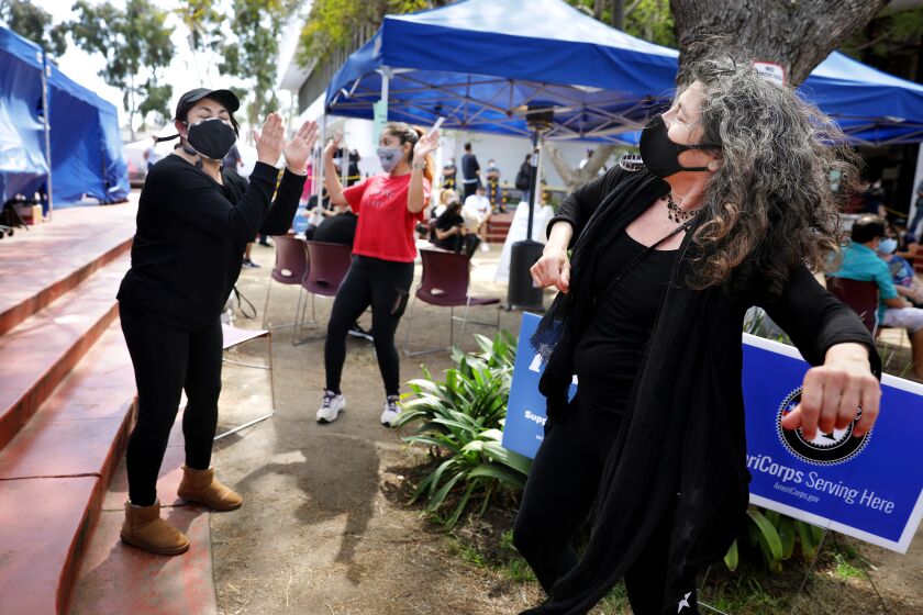 LOS ANGELES-CA-MARCH 22, 2021: Laurie Ginsburg, 58, of Santa Monica, right, dances with Alma De La Rosa, 53, of South Gate, left, and De La Rosa's daughter Andrea, 27, center, after receiving the Covid-19 vaccine at Kedren Community Health Center in South Los Angeles on Monday, March 22, 2021. (Christina House / Los Angeles Times)