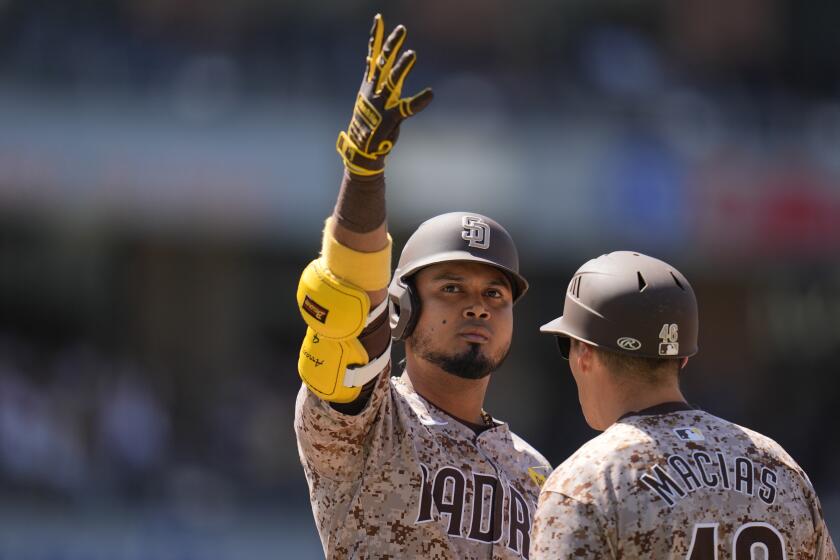San Diego Padres' Luis Arraez, left, celebrates after hitting an RBI single as he stands on first base next to first base coach David Macias during the sixth inning of a baseball game against the New York Yankees, Sunday, May 26, 2024, in San Diego. (AP Photo/Gregory Bull)