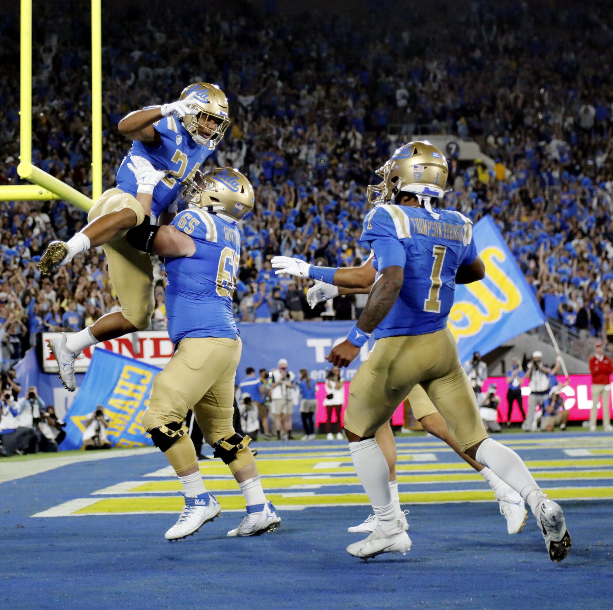  UCLA's Paul Grattan  lifts up running back Zach Charbonnet after a touchdown.