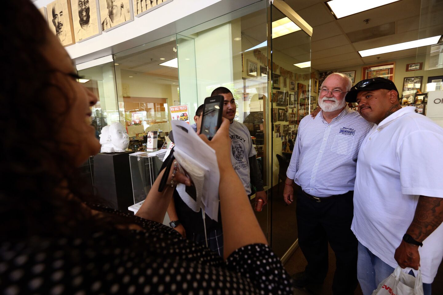 Rosemary Estrada takes a picture of Father Gregory Boyle with one of the men he mentors at Homeboy Industries.