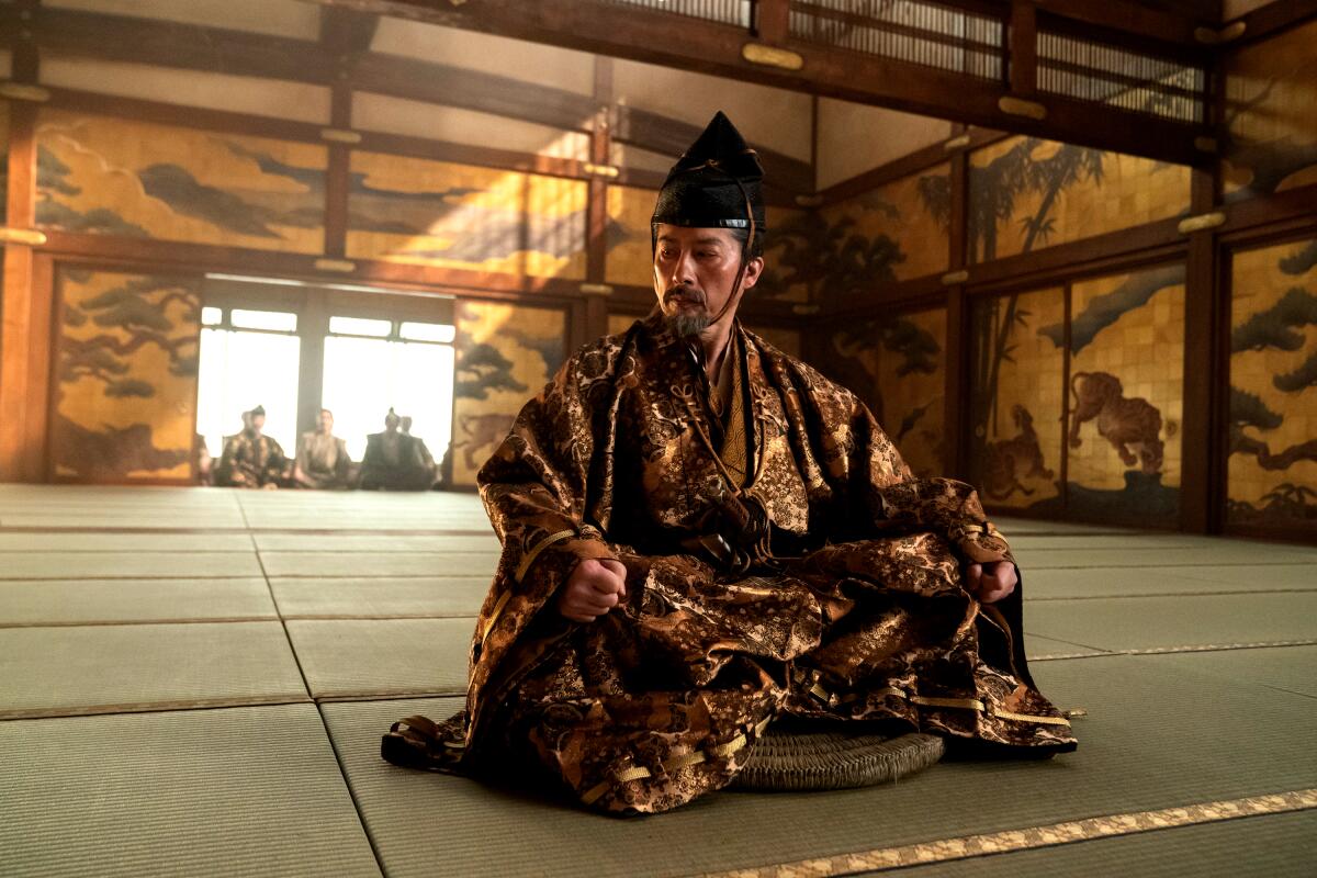 A man dressed in a 17th century Japanese costume sits on a mat in "Shogun."