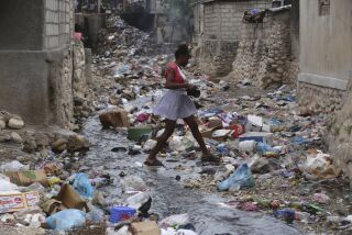 Una niña camina por una calle llena de basura en Puerto Príncipe, Haití, el jueves 13 de julio de 2023. (AP Foto/Odelyn Joseph)